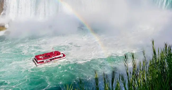 Blue Maid of the Mist boat approaching the powerful Niagara Falls spray